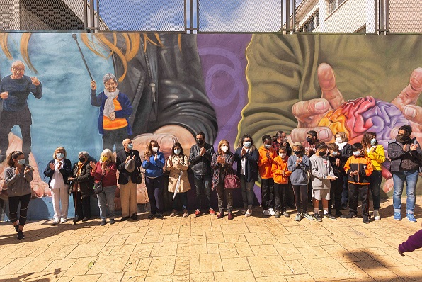 Todas las personas participantes en esta iniciativa posan junto al mural.